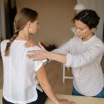 A therapist performing a shoulder massage on a woman to relieve physical tension.