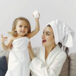A joyful mother and daughter enjoying a playful moment indoors with towels.