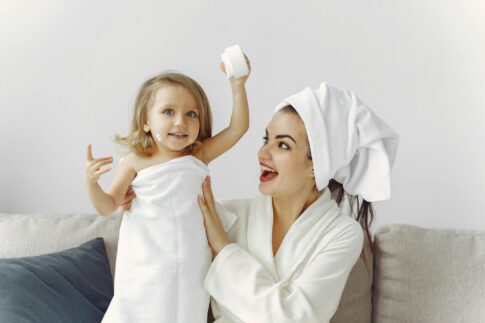 A joyful mother and daughter enjoying a playful moment indoors with towels.