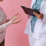 Close-up of a patient consulting a doctor with a clipboard in a medical setting.