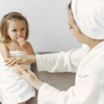 A mother gently interacts with her daughter wrapped in a towel, showcasing warmth and love.