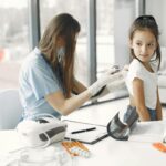 Young girl in clinic receiving a checkup from a female doctor with stethoscope.