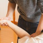 Crop anonymous osteopath massaging injured hand of client in process of treatment procedure