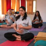 Pregnant women practicing calming prenatal yoga in a serene Rishikesh studio.