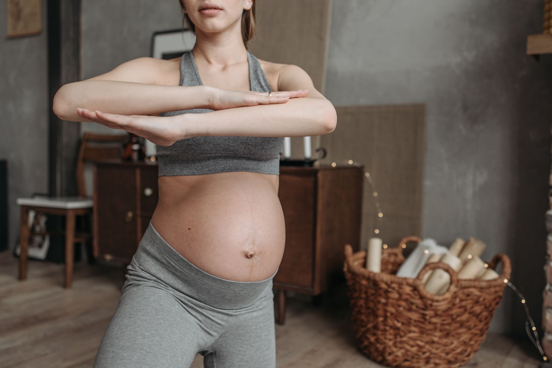 Fit pregnant woman doing yoga indoors, focusing on health and flexibility.