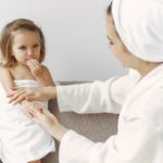 A mother gently interacts with her daughter wrapped in a towel, showcasing warmth and love.