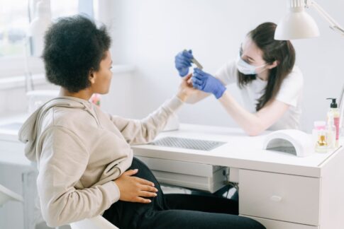A pregnant woman enjoying a manicure at a modern nail salon for self-care and relaxation.