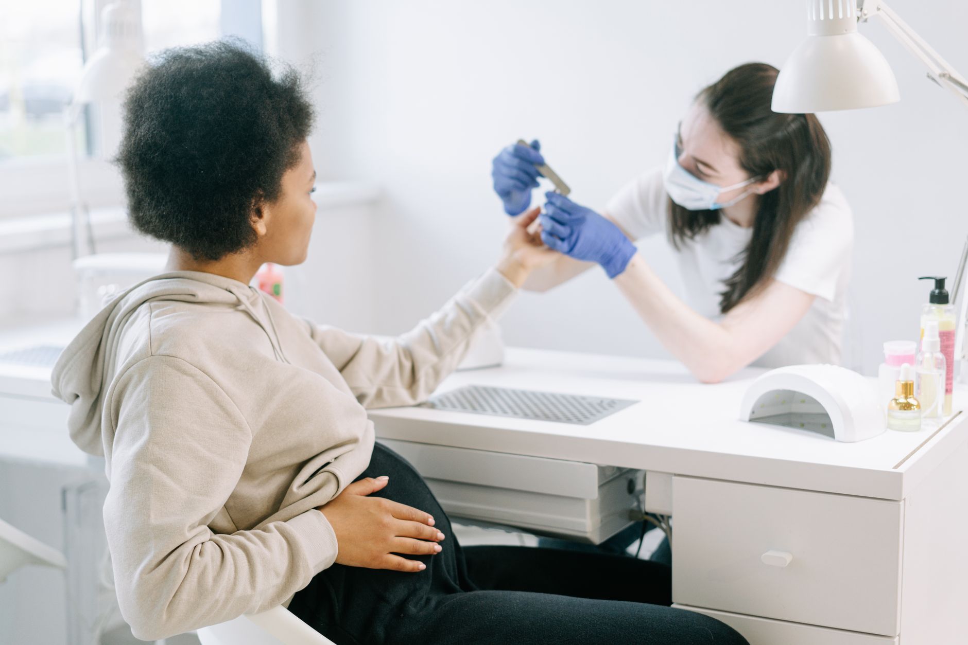 A pregnant woman enjoying a manicure at a modern nail salon for self-care and relaxation.