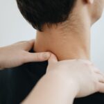 Close-up of a physiotherapist providing neck massage for pain relief in a clinic setting.