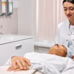 A beautician providing skincare treatment to a woman in a clinic setting, focusing on care and relaxation.