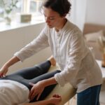 A massage therapist provides care to a lying patient in a tranquil indoor setting.