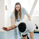A physiotherapist assists a patient in stretching exercises indoors.