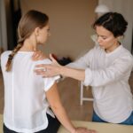 A therapist performing a shoulder massage on a woman to relieve physical tension.
