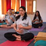 Pregnant women practicing calming prenatal yoga in a serene Rishikesh studio.