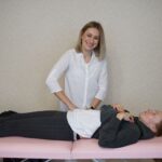 A therapist providing relaxation therapy to a client lying on a massage table indoors.