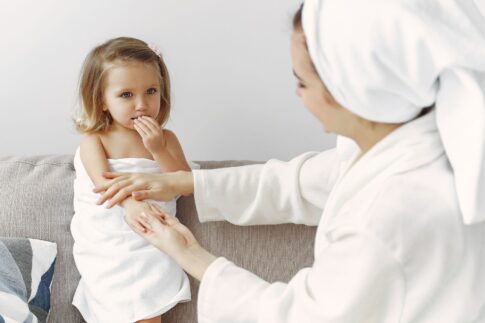 A mother gently interacts with her daughter wrapped in a towel, showcasing warmth and love.