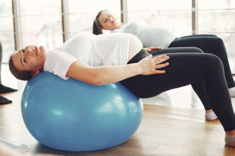 Pregnant women engaging in low-impact exercise with fitness balls indoors.